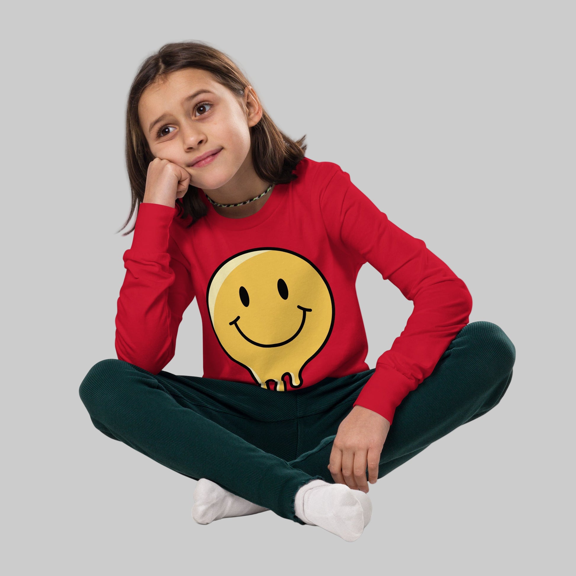 Young girl wearing a red sweater with a smiley face design on a white background