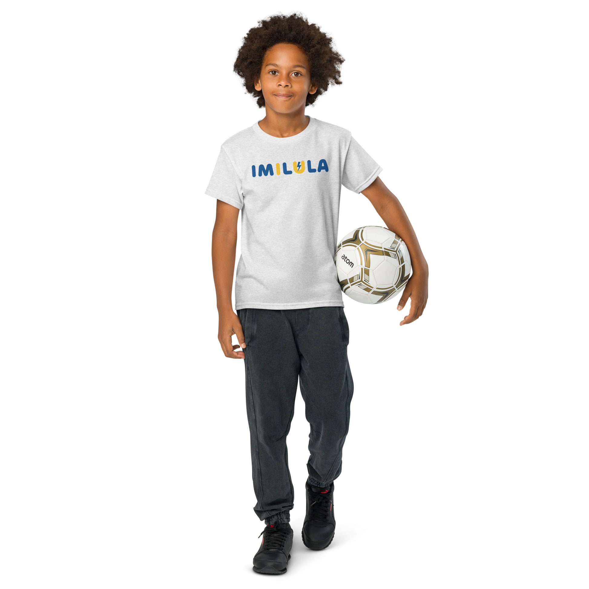 Child holding a soccer ball wearing an 'IMILIA' t-shirt on a white background