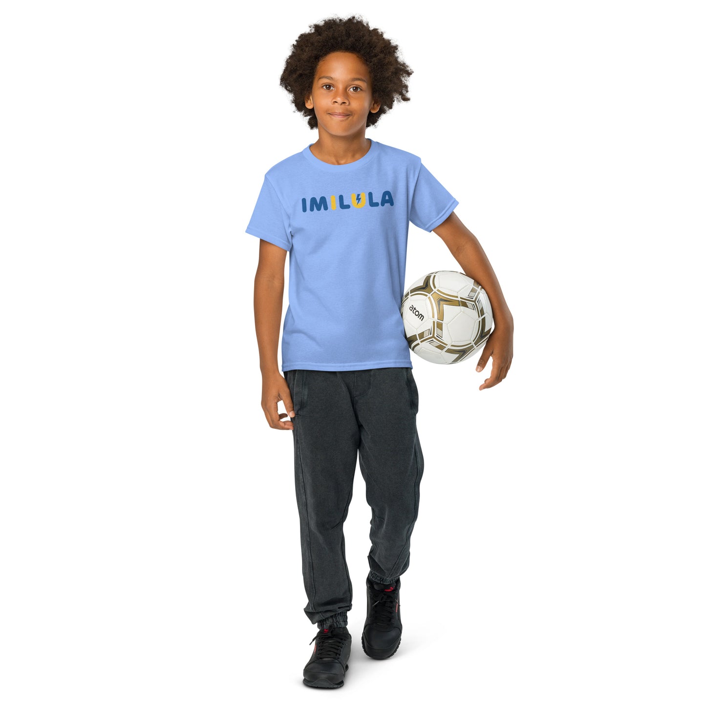 Child wearing a blue t-shirt with a graphic design, holding a soccer ball on a white background