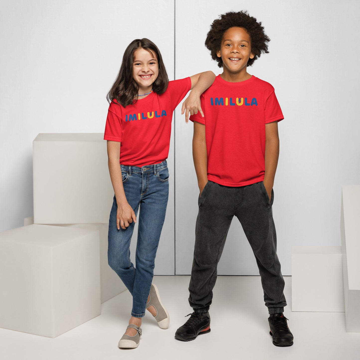 Two children wearing red shirts with 'IMILULA' printed on them, standing against a white background.