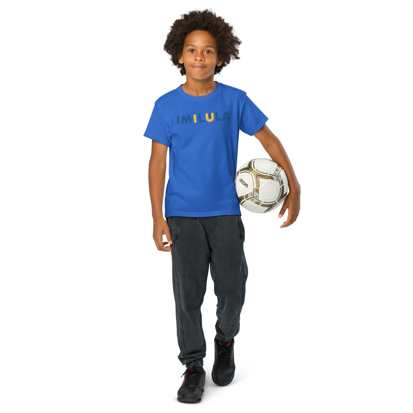Child holding a soccer ball wearing a blue shirt and gray pants on a white background