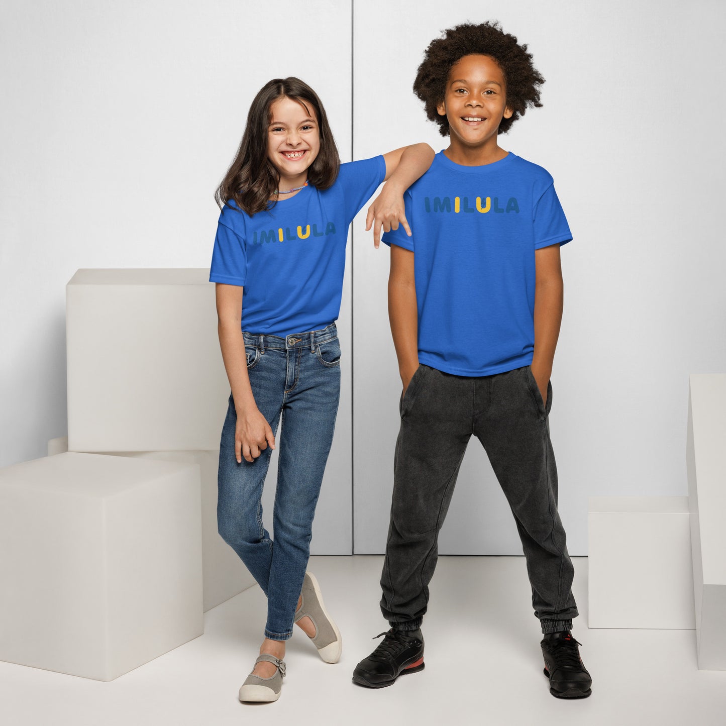 Two children wearing blue t-shirts with a graphic design, standing in a minimalistic setting.
